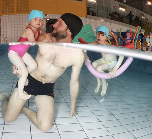 papa avec des enfants nageurs dans la piscine